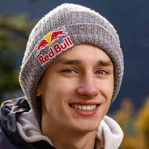In 2025, Josef Šindel poses confidently in Red Bull apparel against an autumnal Ticino, Switzerland backdrop, capturing the brand's adventurous mountain spirit.