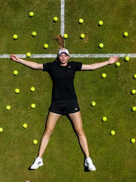 Elena Rybakina allongée sur le gazon de Wimbledon, entourée de balles, à l’approche du tournoi 2025.