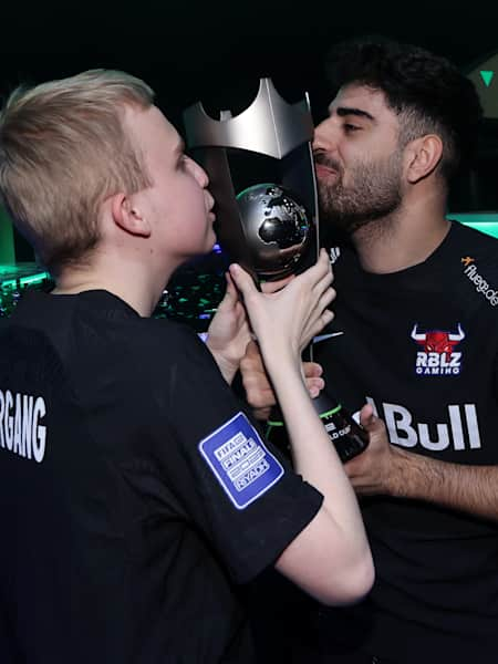 Anders Vejrgang und Umut Gültekin küssen den Pokal nach dem Triumph beim FIFAe World Cup 2023.