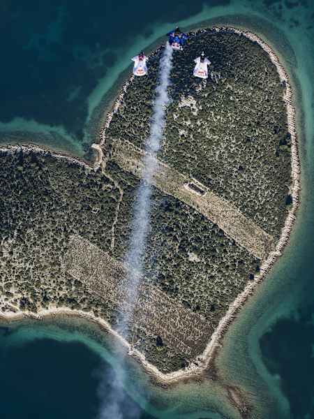 Marco Waltenspiel, Amy Chmelecki y Marco Fuerst vuelan con sus trajes de alas por encima de una isla con forma de corazón, cerca de Zadar, Croacia, el 30 de noviembre de 2016.