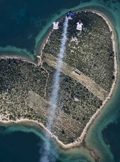 Marco Waltenspiel, Amy Chmelecki and Marco Fuerst fly with their wingsuits above the heart island near Zadar, Croatia, November 30, 2016