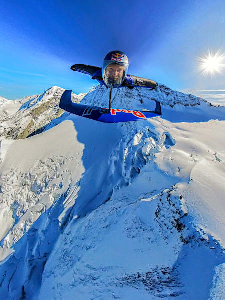 In 2024, Peter Salzmann soars in a wingsuit over snowy Swiss Alps during the Red Bull Wingsuit Foil Project