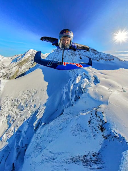 In 2024, Peter Salzmann soars in a wingsuit over snowy Swiss Alps during the Red Bull Wingsuit Foil Project