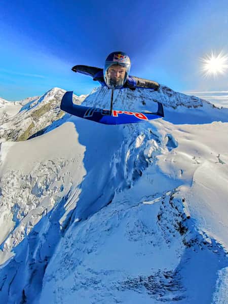 In 2024 zweeft Peter Salzmann in een wingsuit over de besneeuwde Zwitserse Alpen tijdens het Red Bull Wingsuit Foil Project