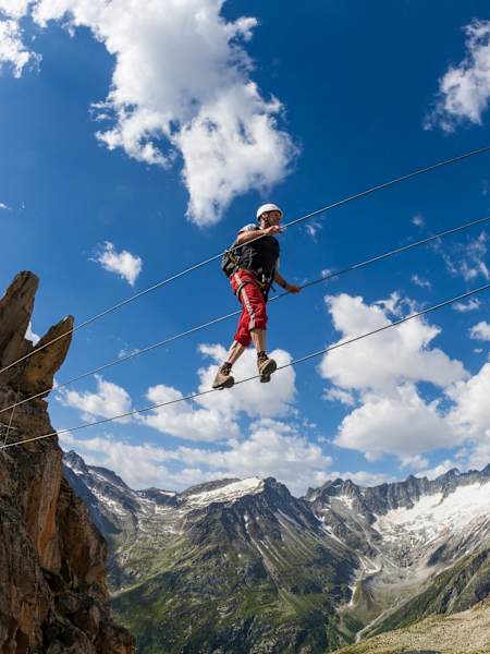 Person crosses wire bridge while taking on the via ferrata in Bergsee, Germany