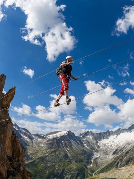 Person crosses wire bridge while taking on the via ferrata in Bergsee, Germany