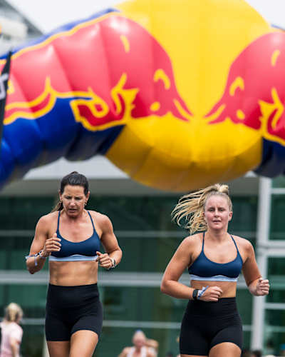 Deux femmes courent l'une à côté de l'autre lors d'une course de fitness HYROX.