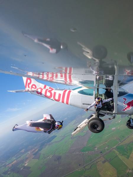 Mike Swanson vole en wingsuit à côté de l'avion Plane Swap (piloté par Luke Aikins) et Jon Devore se penche pour attraper une canette de Red Bull au Red Bull Aviation Camp.