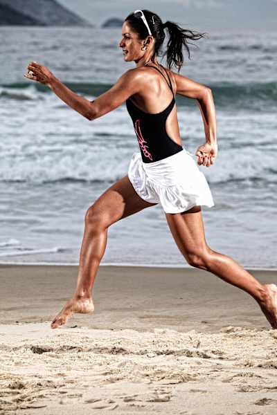 Triathlete Fernando Keller running down a beach.