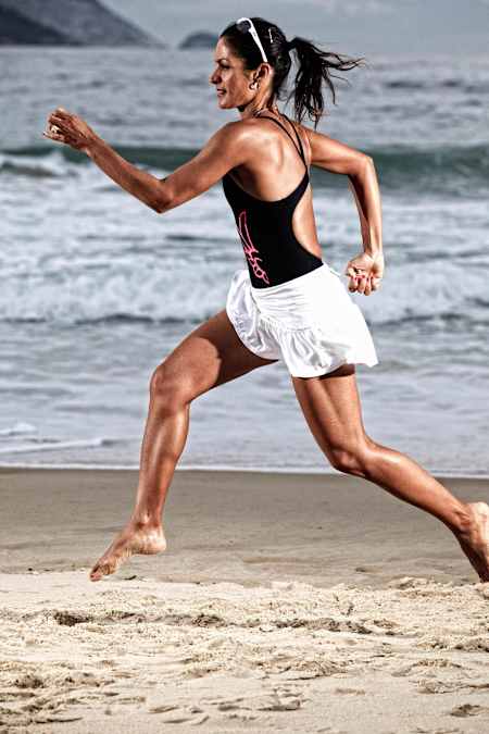 Triathlete Fernando Keller running down a beach.