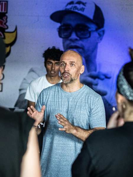B-Boy Storm talking to the students that surround him in a practice room at Red Bull BC One 2018.
