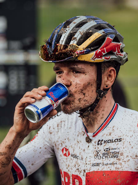 Le cycliste Tom Pidcock boit un Red Bull pendant un entrainement de VTT.
