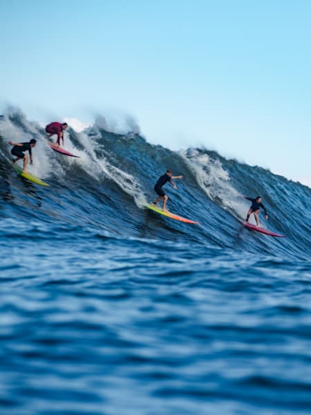 Remi Nealon and participants surf at Waimea Bay, Oahu, Hawaii
