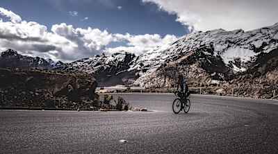 A participant in IncaDivide cycles on a road in the Andes.