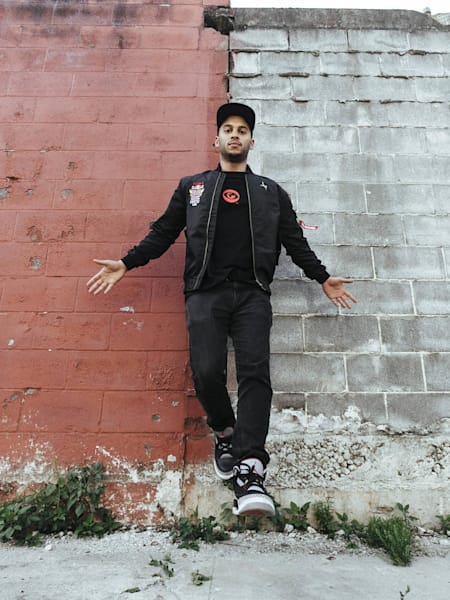 Lean Rock poses in front of a red and white wall.