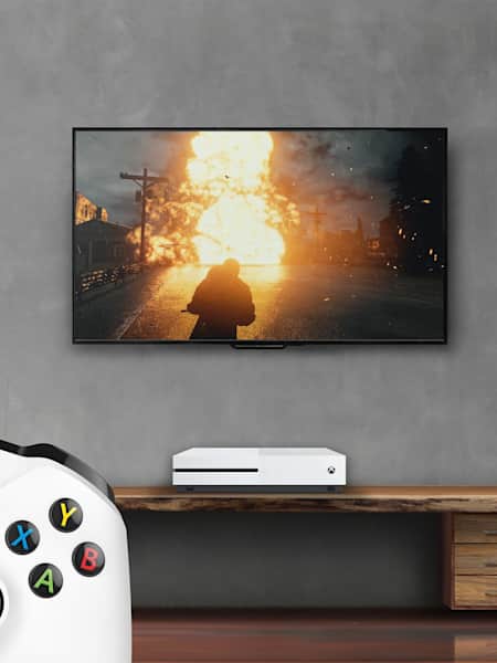 A screenshot of PUBG being played in a house, showing a TV, an Xbox One controller and an Xbox One.