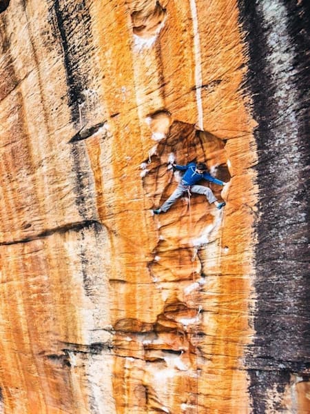 Climber Wiz Fineron rests in an alcove while climbing big sandstone cliffs in Australia, shot by Ken Etzel for Red Bull Illume.
