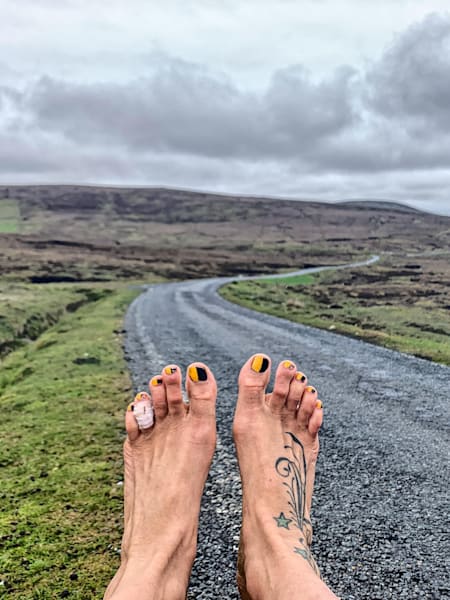 Anna McNuff sits beside the road during Barefoot Britain challenge
