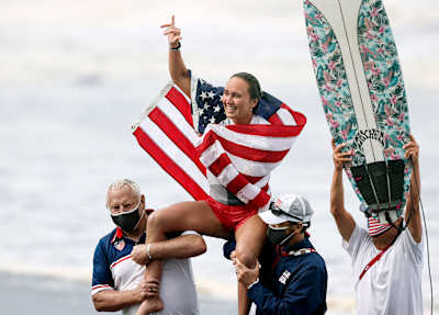 American surfer Carissa Moore celebrating a historic victory with Team USA after a golden run in Tokyo.
