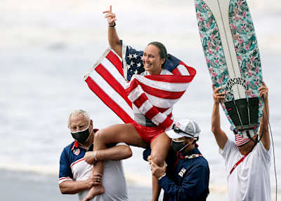 American surfer Carissa Moore celebrating a historic victory with Team USA after a golden run in Tokyo.