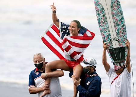 American surfer Carissa Moore celebrating a historic victory with Team USA after a golden run in Tokyo.