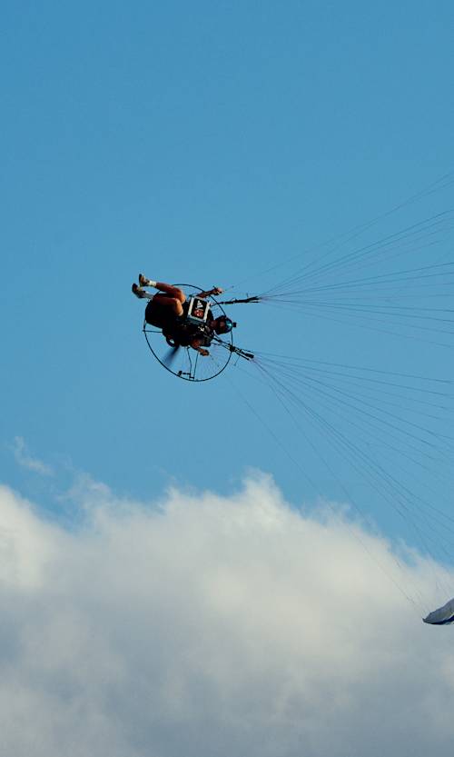 Horacio Llorens performs an exhilarating paragliding stunt above Egypt’s North Coast in August 2025, soaring against a vivid blue sky and clouds.
