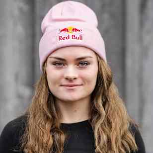 In 2025, Lucy Procter wears a pink Red Bull beanie while posing for a portrait in Thalgau, Austria.