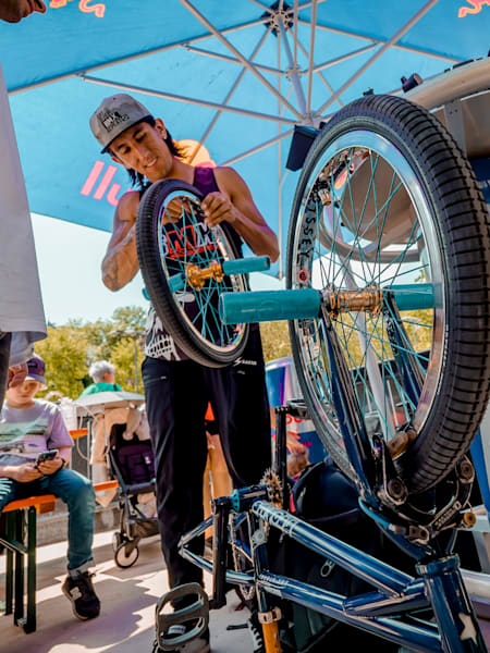 A BMX rider does maintenance to fix their bike during a competiton.