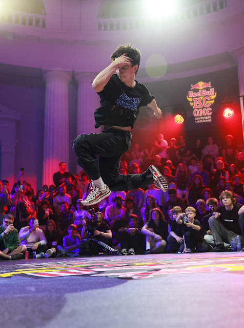 B-Boy Raptor showcases explosive moves at Red Bull BC One Cypher Ukraine 2026 at VDNG in Kyiv, surrounded by an energetic crowd and vibrant stage lights
