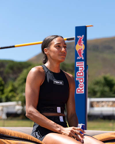Heptathlete Nafi Thiam sitting in front of high jump apparatus, holding a can of Red Bull