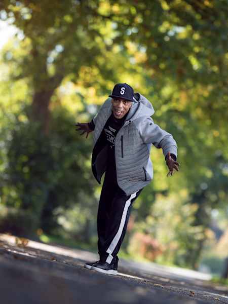 Tony GoGo dances on a street with trees in the background