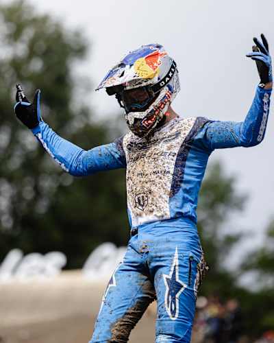 Ronan Dunne revels in victory at the UCI Mountain Bike World Cup 2025 in Les Gets, Haute-Savoie, France, showcasing dynamic energy in a mud-splattered blue suit.