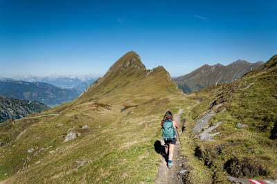 Person walks along mountain trail towards mountain peaks in Zell am See.