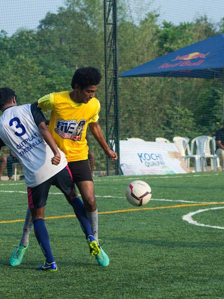 Footballers compete for the ball while playing on the turf ground at Sporthood Espirito, Kochi, Kerala.