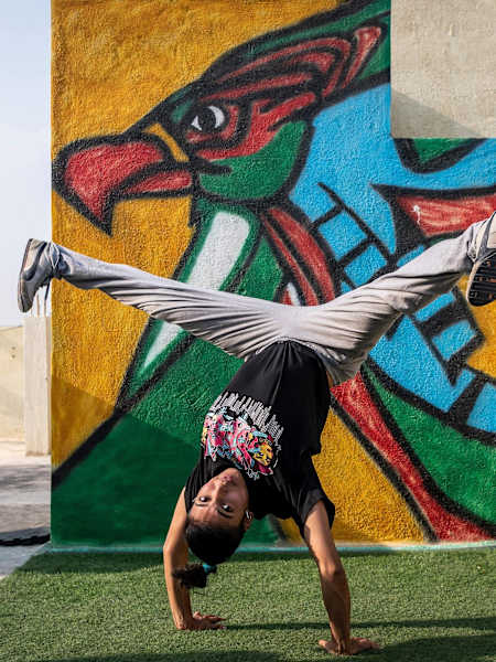 Jo is balancing on her hands with a painted wall in the background