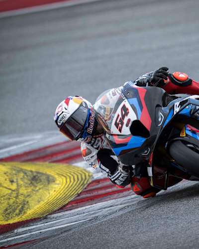 Superbike rider Razgatlıoğlu races around a bend on a track.