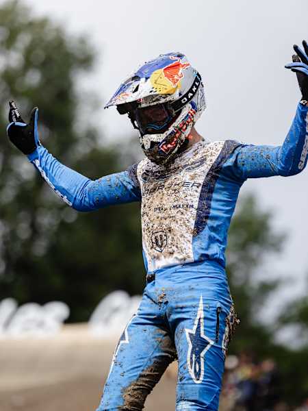 Ronan Dunne revels in victory at the UCI Mountain Bike World Cup 2025 in Les Gets, Haute-Savoie, France, showcasing dynamic energy in a mud-splattered blue suit.