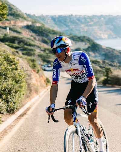 Florian Lipowitz of Red Bull - BORA - hansgrohe is training on Mallorca's scenic roads in December 2025, sporting the vibrant Red Bull cycling kit against a coastal backdrop
