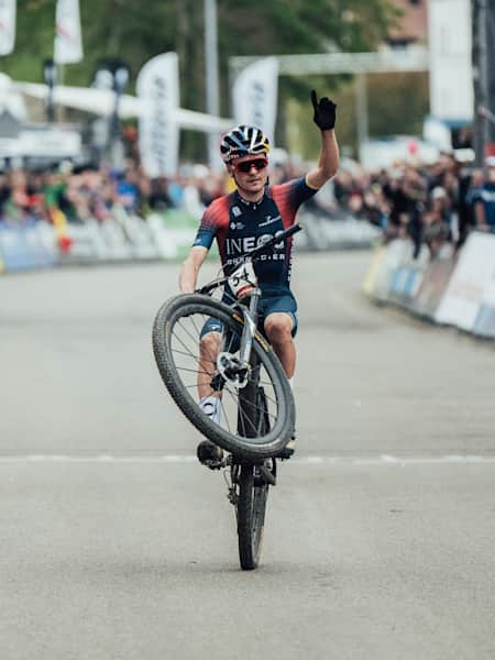 Tom Pidcock fährt mit einem Wheelie über die Ziellinie beim XCO World Cup 2022 in Albstadt, Deutschland. 