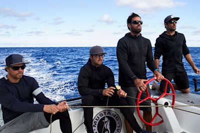Four of the crew members sailing offshore on foiling catamaran.