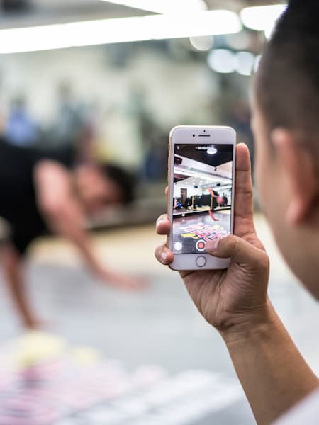 A person shoots a video of a dancer on their phone.