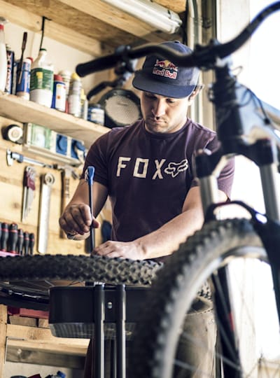 Yannick Granieri works on the spokes of his MTB wheel in his bike shed.