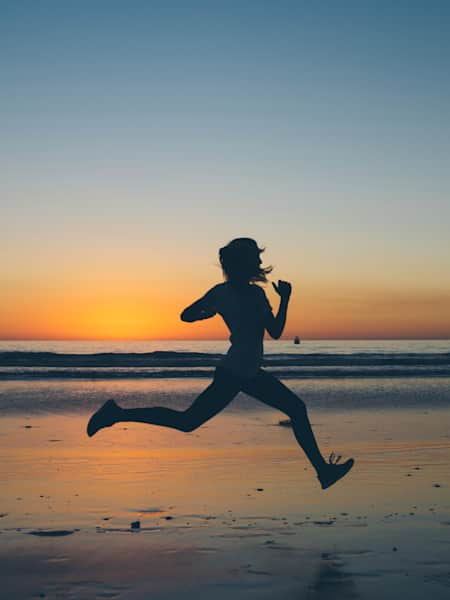 Female Fitness Trainer on the sand beach sunset background