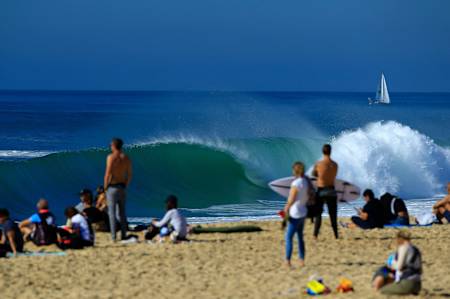 An empty tube breaks in front of a busy beach in Hossegor, France.