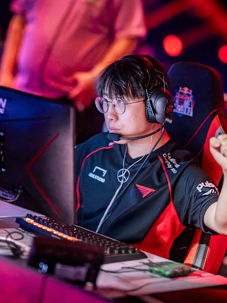 T1 esports team member gears up for intense competition at Red Bull Home Ground 2024 in Berlin, Germany, shown celebrating a team play with a fist bump.