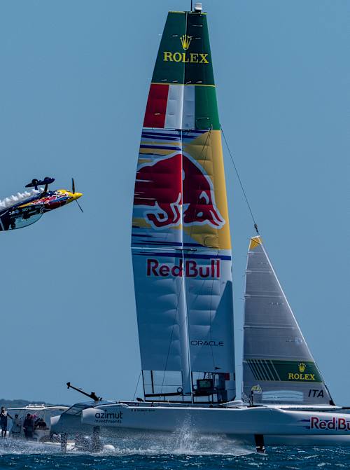 Ein F50-Katamaran für SailGP, mit einem Flugzeug, das Kunststücke vorführt