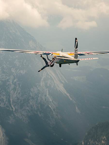 Climber Domen Škofic hangs from the wing of a Blanik glider.