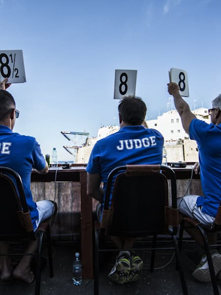 The judges score a dive from the 27.5 metre platform during the seventh stop of the Red Bull Cliff Diving World Series, Polignano a Mare, Italy on September 13th 2015.