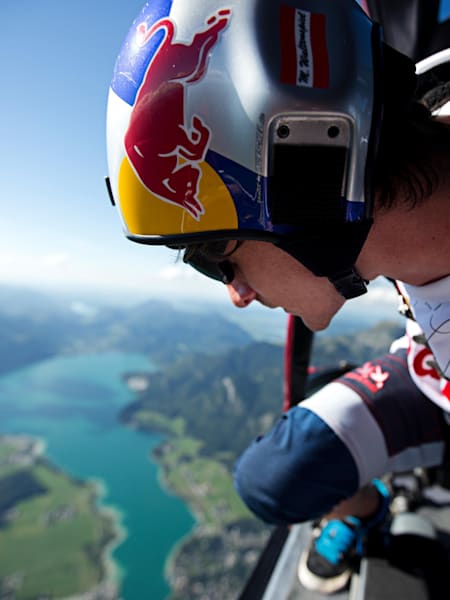 Skydiver waits at side of plane waiting to jump out over a turquoise lake.
