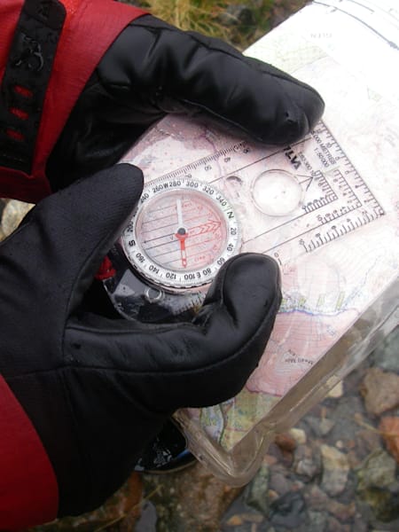Person holds compass over an OS map.